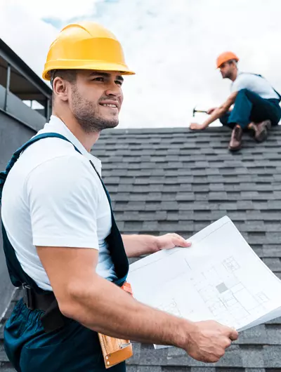 Couvreurs professionnels travaillant sur une toiture avec plan et outils