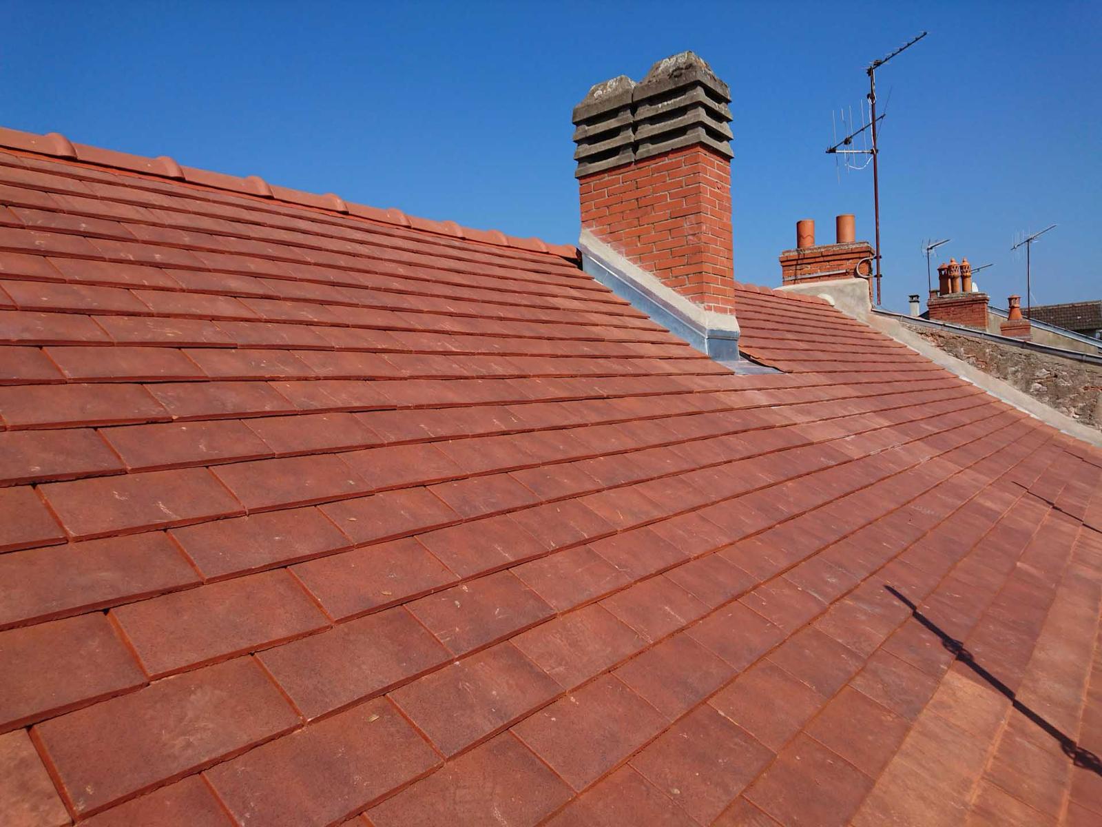 Toiture neuve en tuiles plates rouges avec cheminée rénovée et solins étanches